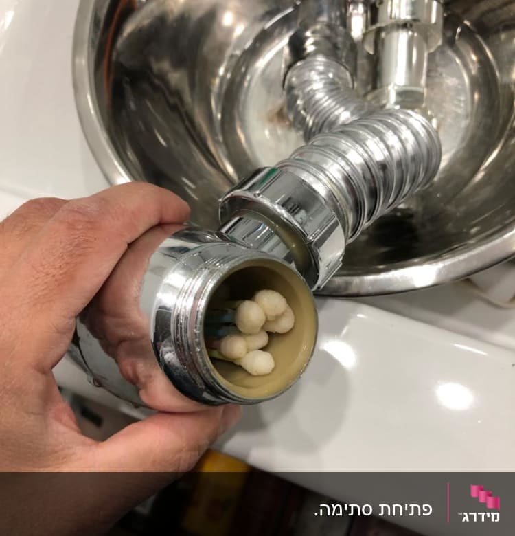יד מחזיקה צינור מתכת עם סתימה בכיור
